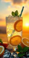 Refreshing citrus beverage with ice and mint in a glass during sunset photo