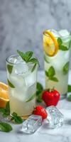 Refreshing summer drinks with mint, lemon, and strawberries on marble countertop photo