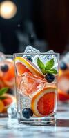 Refreshing fruit cocktail with ice and mint displayed in a clear glass on a marble surface photo