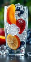 Refreshing summer drink with fresh fruits and ice in a clear glass on a sunny day photo