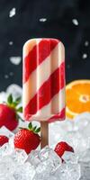 Colorful striped popsicle surrounded by fresh strawberries and ice on a dark background photo