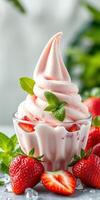 Delicious strawberry soft serve dessert served in a glass cup garnished with fresh mint leaves photo