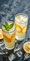 Refreshing lemonade with fresh mint and ice served in tall glasses on a dark surface surrounded by lemon slices photo