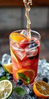Refreshing summer cocktail with colorful fruits and ice in a glass on a bright table photo