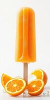 Frozen orange popsicle sitting on ice surrounded by fresh oranges on a bright background photo