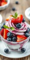 Fresh dessert with strawberries and blueberries served in a glass bowl topped with mint on a wooden table photo