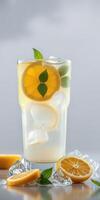 Refreshing citrus drink with mint and ice served in a tall glass on a light background photo