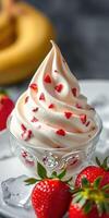 Delicious soft serve ice cream topped with fresh strawberry pieces and served in a decorative glass bowl photo