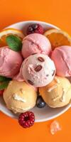 Delicious assortment of colorful ice cream served in a bowl with fresh fruits and nuts on a bright orange background photo