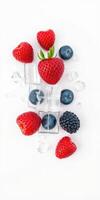 Fresh berries and ice cubes arranged creatively on a white background for a refreshing summer treat photo