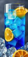 Refreshing blue citrus drink with ice and lemon slices in a tall glass on a dark background photo