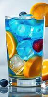Refreshing blue drink with fruit and ice in a glass on a bright surface photo