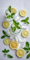 Refreshing mint lemonade served in glasses with fresh lemon slices and ice cubes on a light background photo