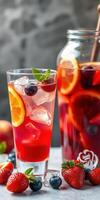 Refreshing berry and citrus beverage served in a glass with ice beside a jar on a marble surface photo