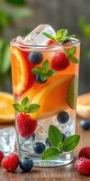 Refreshing fruit cocktail with mint, ice, and vibrant colors in a clear glass photo