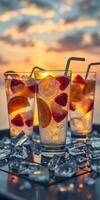 Refreshing summer drinks served with ice and fruit at sunset by the beach photo