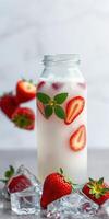 Refreshing strawberry drink garnished with mint and ice beside fresh strawberries on a gray table photo