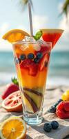 Colorful fruit cocktail garnished with berries and citrus at a sunny beach setting photo