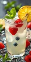 Refreshing berry lemonade served in a glass with mint leaves and ice cubes on a summer day photo