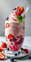Delicious berry and cream dessert served in a tall glass with fresh fruits and mint garnish photo
