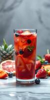 Refreshing summer drink with berries and citrus in a tall glass on a marble surface photo
