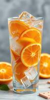 Refreshing orange beverage with ice cubes and sliced oranges on a marble countertop photo