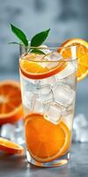 Refreshing citrus drink with ice cubes and orange slices on a serene blue background ready for summer enjoyment photo