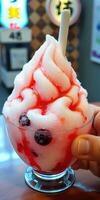 Soft-serve dessert topped with vibrant cherry syrup and blueberries enjoyed in a lively setting photo