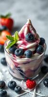 Creamy dessert with fresh blueberries and strawberries served in a glass cup, topped with syrup and mint leaf photo