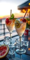 Refreshing cocktails with fresh fruit garnishes at sunset by the seaside photo