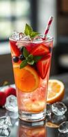 Colorful fruit cocktail with berries and mint garnished with a striped straw in a glass on a table photo