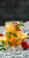 Refreshing fruit cocktail with mint and ice served in a glass on a table with citrus fruit and strawberries photo