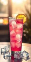 Refreshing pink beverage served in a tall glass with ice and a slice of orange during a sunny evening photo