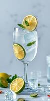 Refreshing lemonade cocktail served with fresh lemon slices and mint leaves in a clear glass on a marble countertop photo