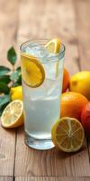 Refreshing citrus drink garnished with lemon slices and surrounded by fresh lemons and oranges on wooden surface photo