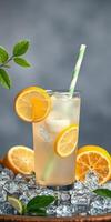 Refreshing lemonade served in a tall glass with ice and lemon slices against a gray background photo