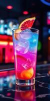 Colorful cocktail garnished with citrus fruits served in a glass at a lively bar during nighttime photo