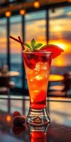 Vibrant cocktail garnished with mint and fruit against a stunning sunset backdrop photo