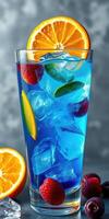 Refreshing blue beverage served in a tall glass garnished with orange slices and mixed berries on a gray background photo