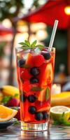 Refreshing fruit cocktail served in a tall glass at a vibrant outdoor setting during a sunny day photo