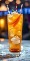 Refreshing beverage served in a tall glass with ice, fruit garnish, and straws at a vibrant bar in the evening photo