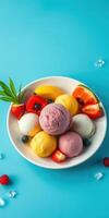 Colorful bowl of assorted ice cream scoops with fresh fruits on a vibrant blue background photo