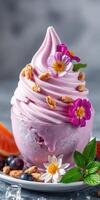 Delicious swirl of pink yogurt topped with edible flowers and fruits served in a glass bowl photo
