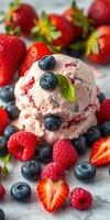 Delicious berry ice cream topped with fresh strawberries, raspberries, and blueberries served on a marble counter photo