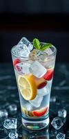 Refreshing summer drink with ice, citrus, and mint served in a glass on a dark tabletop photo