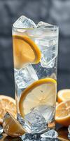 Refreshing lemon beverage served with ice in a clear glass with lemon slices on a blurred background photo