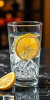 Refreshing glass of cold water with lemon slice and ice on a marble table in a warm setting photo
