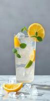 Refreshing lemon and mint drink served in a tall glass on a marble surface with ice and lemon slices photo