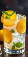 Refreshing lemon drink garnished with mint served over ice in a glass on a wooden table photo