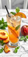Refreshing peach iced tea garnished with mint leaves on a marble countertop during sunny afternoon photo